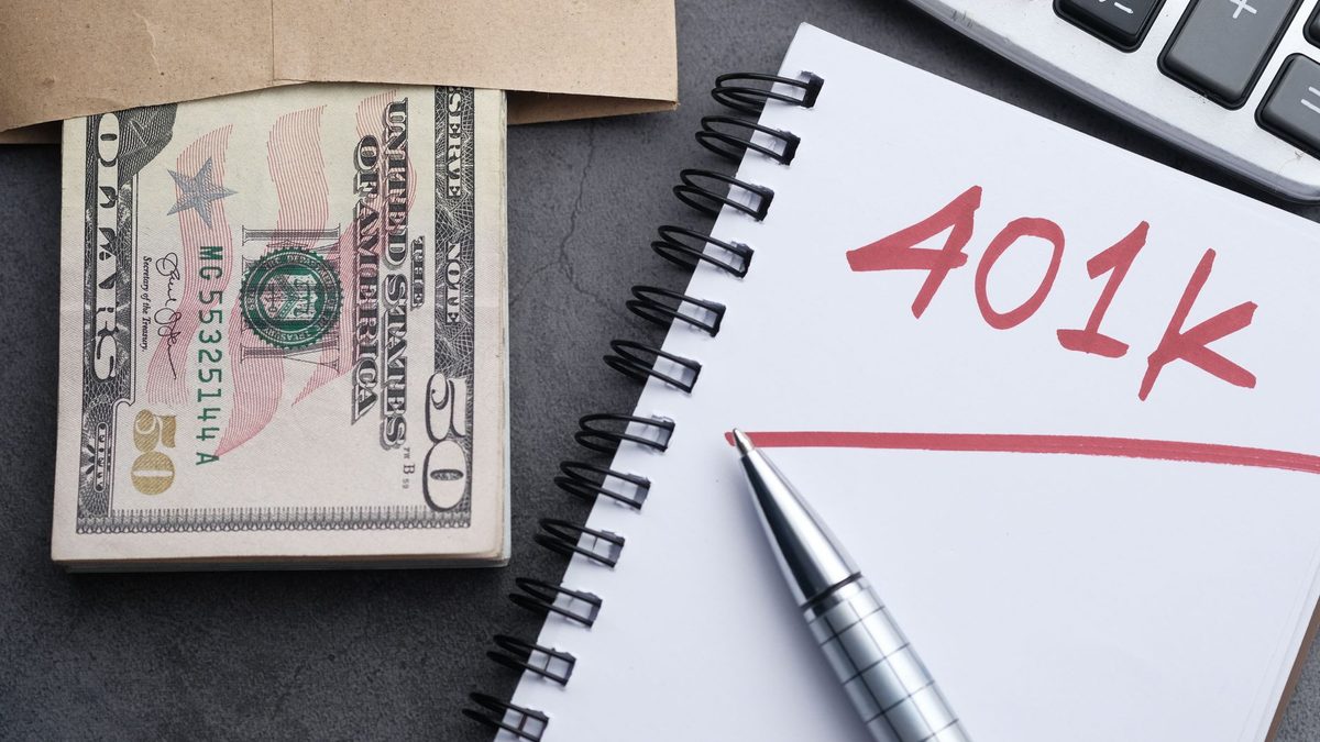 A desk setup with a notebook labeled '401k', a pen, cash, and a calculator representing financial planning.