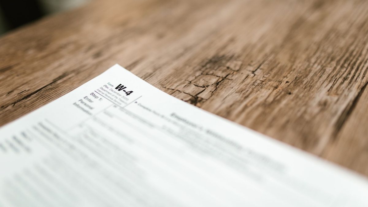 Close-up of a W-4 form resting on a rustic wooden table, highlighting textures.