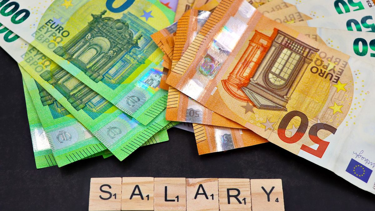 Euro banknotes alongside wooden Scrabble letters spelling 'salary' symbolize financial earnings and payroll.