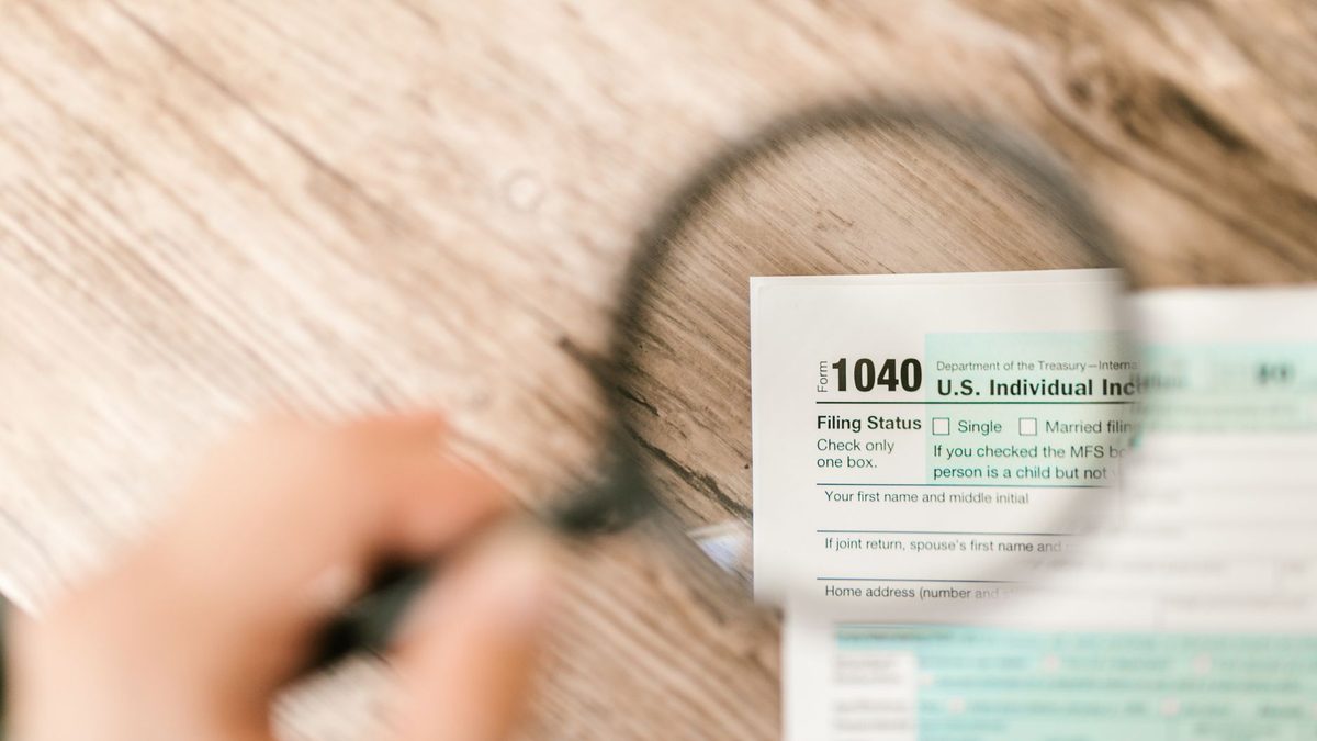 Close-up image of IRS Form 1040 under a magnifying glass on a wooden surface.